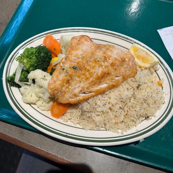 Carpo's Restaurant's American dish with a large fish fillet, rice, broccoli, cauliflower, carrots, and a lemon wedge.
