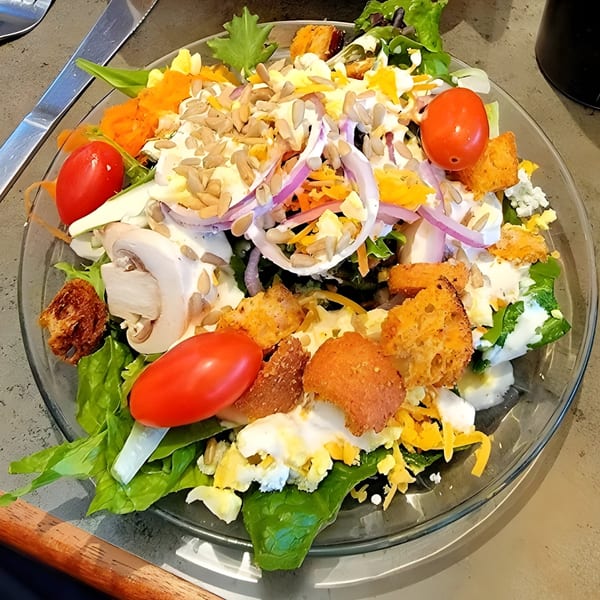 A vibrant Carpo's Restaurant salad with lettuce, tomatoes, mushrooms, onions, croutons, and sunflower seeds.